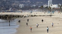 Semua orang berjalan pada jarak yang aman di Venice Breach pada 23 Maret 2020 di Venice, California. Tempat parkir di sejumlah pantai populer termasuk Venesia dan pantai Santa Monica ditutup setelah kerumunan terlihat di beberapa pantai akhir pekan ini selama pandemi coronavirus. Walikota Los Angeles Eric Garcetti juga mendesak Angelenos untuk mulai menerapkan social distancing atau jarak fisik untuk memperlambat penyebaran COVID-19. Getty Images/Mario Tama.