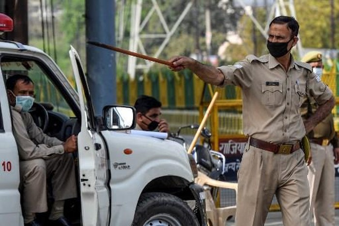 Polisi India pukuli pemotor A police personnel instructs a motorist to go back at a checkpoint during a government-imposed lockdown as a preventive measure against the spread of the COVID-19 novel coronavirus, in Ghaziabad on March 24, 2020. (Photo by Prakash SINGH / AFP)