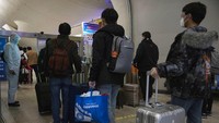 Sejumlah penumpang mengantre untuk diperiksa kesehatannya saat tiba di Wuhan.