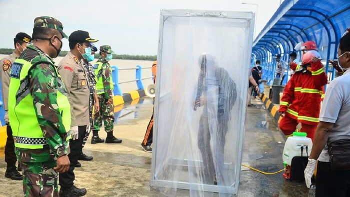 Sebanyak 15 TKI yang baru tiba dari Malaysia disemprot disinfektan.