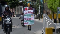 Seorang pria berkeliling sambil mengenakan topeng dan membawa sejumlah imbauan guna mengajak masyarakat membantu penanganan virus Corona (COVID-19) di Palu, Sulawesi Tengah, Minggu (29/3/2020).