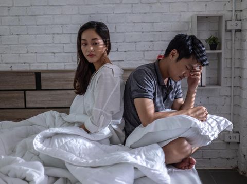 Young couple in love lying on bed at home and cuddling, embracing and enjoying weekend together