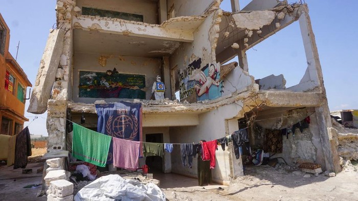 A member of the Syrian civil defence, known as the White Helmets, disinfects a former school building currently inhabited by displaced families in the rebel-held town of Binnish in Syrias northwestern Idlib province, on March 26, 2020, as part of the efforts to prevent the spread of the coronavirus epidemic. (Photo by Muhammad HAJ KADOUR / AFP)