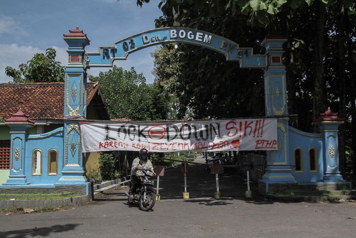 Warga melintas di depan spanduk penutupan jalan masuk Desa Kalasan, Sleman, DI Yogyakarta, Senin (30/3/2020). Sejumlah desa atau perkampungan di Kota dan Kabupaten di DI Yogyakarta memberlakukan akses satu pintu masuk dengan menutup sejumlah jalan untuk mengurangi aktivitas warga sebagai upaya mencegah penularan COVID-19. ANTARA FOTO/Hendra Nurdiyansyah/aww.