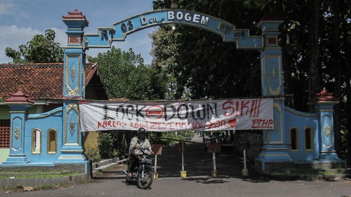 Warga melintas di depan spanduk penutupan jalan masuk Desa Kalasan, Sleman, DI Yogyakarta, Senin (30/3/2020). Sejumlah desa atau perkampungan di Kota dan Kabupaten di DI Yogyakarta memberlakukan akses satu pintu masuk dengan menutup sejumlah jalan untuk mengurangi aktivitas warga sebagai upaya mencegah penularan COVID-19. ANTARA FOTO/Hendra Nurdiyansyah/aww.