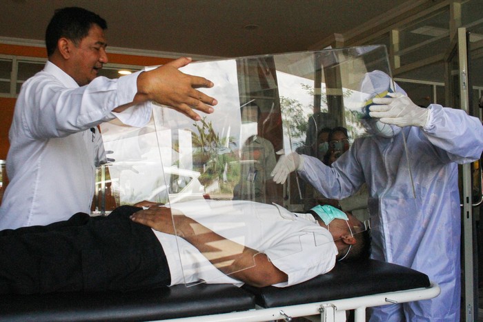 Petugas medis memperagakan penggunaan bilik pengaman hasil inovasi tim pengajar dan mahasiswa di Rusunawa, Universitas Muhammadiyah Malang, Jawa Timur, Senin (30/3/2020). Inovasi bilik pengaman untuk pasien COVID-19 tersebut diharapkan mampu melindungi tenaga medis agar tidak terpapar virus Corona. ANTARA FOTO/Ari Bowo Sucipto/aww.