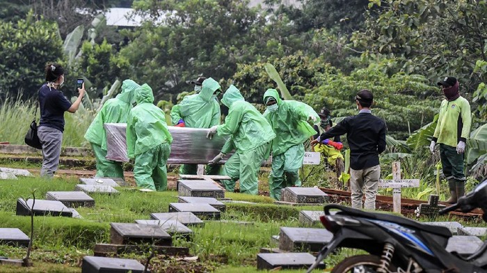Petugas pemakaman menurunkan peti jenazah pasien COVID-19 di TPU Pondok Ranggon, Jakarta, Senin (30/3/2020). Juru bicara pemerintah untuk penanganan COVID-19 Achmad Yurianto per Senin (30/3/2020) pukul 12.00 WIB menyatakan jumlah pasien positif COVID-19 di Indonesia telah mencapai 1.414  kasus, pasien yang telah dinyatakan sembuh sebanyak 75 orang, sementara kasus kematian bertambah delapan orang dari sebelumnya 114 orang menjadi 122 orang. ANTARA FOTO/Muhammad Adimaja/foc.