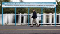 Seorang warga melintas di papan nama  kota  Llanfairpwllgwyngyllgogerychwyrndrobwllllantysiliogogogoch di stasiun kereta kota itu, Wales, Inggris, (6/10/2008).