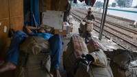 Pekerja mengangkut barang yang akan dikirim melalui kereta api. 