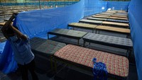 Seorang pekerja India memperbaiki partisi di pusat karantina di kompleks olahraga Sarusojai di Gauhati, India, Sabtu (28/3/2020). Karena keterbatasan tempat mereka membuat tempat karantina seadanya untuk pasien COVID-19. AP Photo/Anupam Nath.
