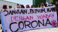 Warga membentangkan sejumlah spanduk saat berunjuk rasa di depan Puskesmas Sidodadi, Kecamatan Candi, Sidoarjo, Jawa Timur, Selasa (31/3/2020).