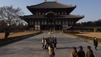 Turis berhenti sejenak untuk berfoto di depan aula utama kuil Todaiji di Nara, Jepang, 17 Maret 2020. Nara adalah salah satu kota Jepang pertama yang terkena COVID-19 pada akhir Januari, ketika seorang sopir bus wisata di kota dinyatakan positif terkena virus. AP Photo/Jae C. Hong.