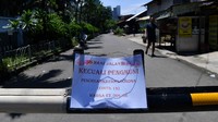 Warga melintas di dekat portal yang menutup akses jalan di Kampung Simprug Golf 2, Kebayoran Lama, Jakarta Selatan, Selasa (31/3/2020).