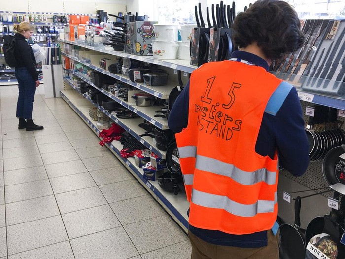 Employees of the Action supermarket wear a safety vest asking customers to keep 1.5 meters, five feet, safe distance, in Amsterdam, Tuesday, March 24, 2020. The country has come to a near standstill as the government sought to prevent the further spread of coronavirus. For most people, the new coronavirus causes only mild or moderate symptoms, such as fever and cough. For some, especially older adults and people with existing health problems, it can cause more severe illness, including pneumonia. (AP Photo/Peter Dejong)