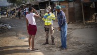 Seorang perwira polisi Afrika Selatan berbicara kepada penduduk kota Alexandra yang berpenduduk padat di sebelah timur Johannesburg, Jumat (27/3/2020). Afrika Selatan melakukan Lockdown secara nasional selama 21 hari dalam upaya untuk mengurangi penyebaran virus Corona, tetapi di Alexandra, banyak orang-orang berkumpul di jalanan tanpa menghiraukan imbauan pemerintah dan mengabaikan kesehatan. AP Photo/ Jerome Delay.