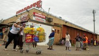 Seorang wanita dan ibunya, mendorong troli belanja melalui tempat parkir di sebuah supermarket di sebuah titik pembayaran hibah sosial di Thokoza, sebelah timur Johannesburg, Afrika Selatan, Senin (30/3/2020). AP Photo/Themba Hadebe.