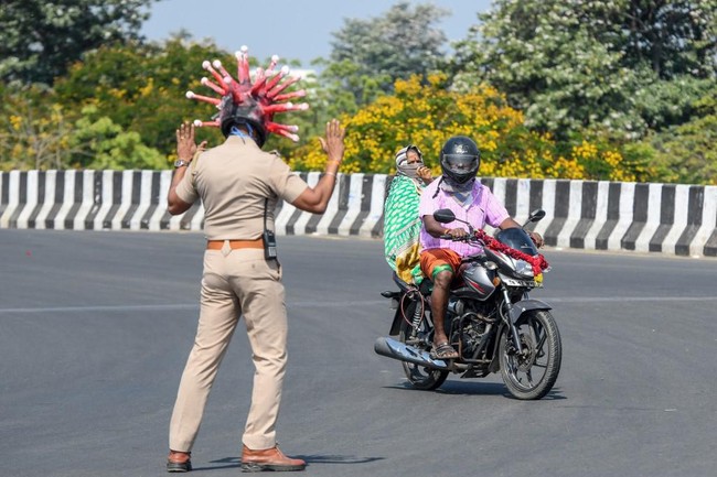 Aksi Rajesh menggunakan helm corona lantas berujung viral. Tak sedikit netizen yang mengapresiasi kinerja sang polisi serta karya desainer tersebut. (Foto: AFP/ARUN SANKAR)
