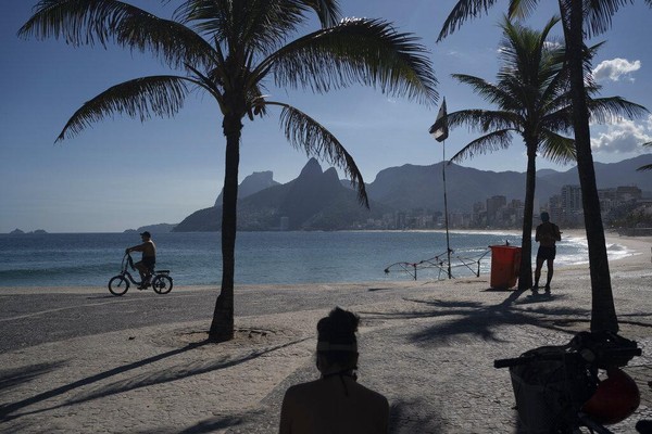 Seorang pria mengendarai sepedanya di sepanjang pantai Arpoador yang kosong di Rio de Janeiro, Brasil, Kamis, 26 Maret 2020, karena banyak orang yang tinggal di rumah untuk membantu menahan penyebaran virus Corona. AP Photo/Leo Correa.