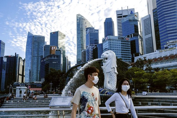 Pasangan mengenakan masker berjalan melewati patung Merlion di Singapura. Pariwisata andalan di wilayah Asia ini turun hingga 27%. AP Photo/Ee Ming Toh. Pasangan mengenakan masker berjalan melewati patung Merlion di Singapura. Pariwisata andalan di wilayah Asia ini turun hingga 27%. AP Photo/Ee Ming Toh.