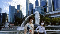 Pasangan mengenakan masker berjalan melewati patung Merlion di Singapura. Pariwisata andalan di wilayah Asia ini turun hingga 27%.  AP Photo/Ee Ming Toh.