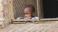 Seorang anak memandang keluar dari balkon di sebuah blok apartemen di Harare, Zimbabwe, Senin (30/3/2020). Pemerintah Zimbabwe mengumumkan untuk melakukan pembatasan wilayah atau lockdown selama tiga pekan untuk memerangi penyebaran virus Corona. AP Photo/Tsvangirayi Mukwazhi.  