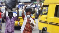 Seorang wanita yang mengenakan masker saat berjalan di seberang Masjid Pusat Lagos, Nigeria, Jumat (20/3/2020). AP Photo/Sunday Alamba.  
