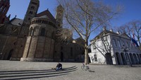 Seorang pria duduk di Alun-alun Vrijthof yang kosong di pusat Maastricht, Belanda Selatan. Tak ada aktivitas kerumunan orang seperti biasanya.