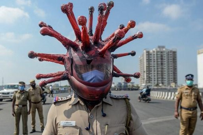 Bukan Rajesh yang membuatnya, melainkan seniman lokal bernama Gowtham. Ia membingkai bagian luar helm dengan kelir merah dan menempelkan kertas yang menyerupai mahkota virus corona. (Foto: AFP/ARUN SANKAR)