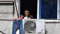 Salah satu warga menikmati makanannya di jendela rumahnya. (dok Reuters)