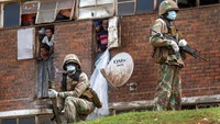 Pasukan Pertahanan Nasional Afrika Selatan berpatroli di Mens Hostel di kota padat penduduk Alexandra di timur Johannesburg. Sejak Sabtu (28/3/2020) Lockdown telah dilakukan dalam upaya mengendalikan penyebaran virus Corona disana. AP Photo/Jerome Delay