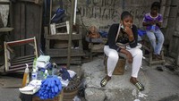 Seorang wanita menjual pembersih tangan dan sarung tangan di sebuah toko yang ditutup sebagian di pasar Balagun yang sibuk. Sementara sebagian besar toko ditutup karena larangan pemerintah pada operasi bisnis yang tidak penting dan pasar untuk menghentikan penyebaran virus Corona, di Lagos, Nigeria Kamis (26/3/2020). AP Photo/Sunday Alamba.