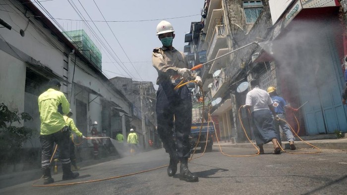 Members of the Myanmar Red Cross disinfect a street as a preventive measure against the COVID-19 coronavirus in Yangon on March 29, 2020. (Photo by Sai Aung Main / AFP)