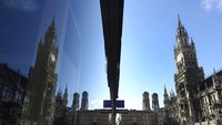 Balai kota dan Marienplatz yang kosong tercermin di jendela toko di pusat kota di Munich, Jerman, Senin, 30 Maret 2020. Untuk memperlambat penyebaran virus Corona, pemerintah federal telah sangat membatasi kehidupan publik. AP Photo/Matthias Schrader.  