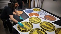 Desainer produk Hatch Exhibits membuat stiker petunjuk sosial distancing. Perusahaan yang biasa menyediakan properti pameran tersebut banting setir dengan membuat APD Corona karena sepinya order pameran.