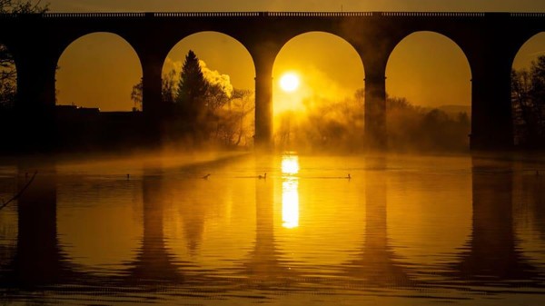 Matahari terbit di belakang jembatan kereta api melintasi lembah Ruhr di Jerman utara (Jonas Güttler/AFP/Getty Images/CNN)