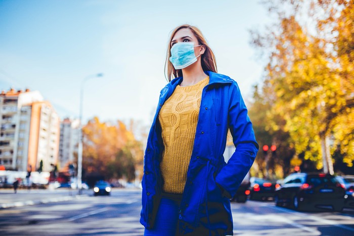 ilustrasi wanita pakai masker Young woman wearing face mask because of air pollution in the city