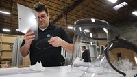Karyawan memeriksa lembaran plastik pelindung wajah dalam proses produksi. Sehari-hari, perusahaan yang berlokasi di Elkridge (45 km utara Washington DC) itu membuat perlengkapan promosi, pameran atau event organizer.