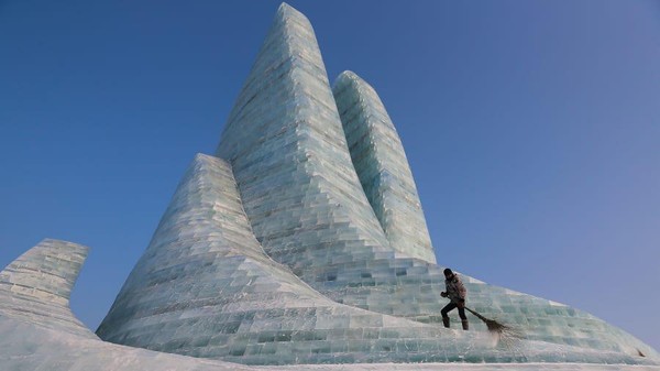 Festival Patung Es dan Salju Internasional Harbin disebut sebagai festival musim dingin terbesar di dunia. Seorang pekerja memelihara salah satu pahatan es (Lintao Zhang/Getty/CNN)