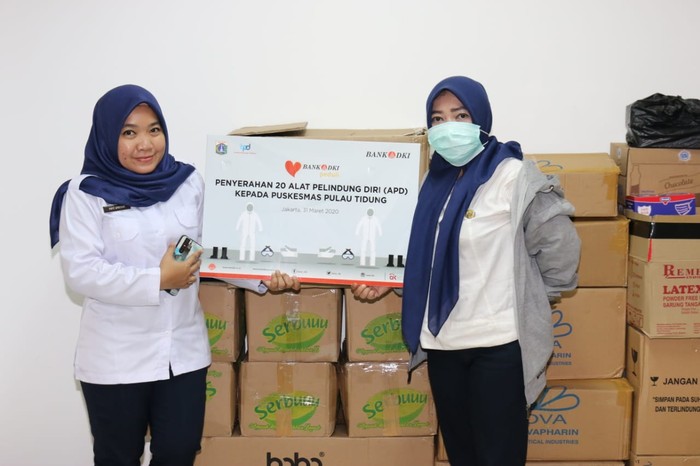 Bantuan APD untuk Tenaga Medis Tenaga medis Puskesmas Pulau Tidung berfoto bersama usai melakukan simbolis penyerahan bantuan CSR Bank DKI berupa 20 (dua puluh) Alat Pelindung Diri kepada Puskesmas Pulau Tidung dalam rangka penanganan pandemi virus Covid-19 di Jakarta, (1/4). Bank DKI juga akan memberikan APD kepada tenaga medis di RSUD-RSUD di DKI Jakarta. Selain memberikan APD, Bank DKI juga menyalurkan donasi kemanusiaan sebesar Rp190 juta yang diberikan kepada tenaga medis yang akan dikoordinasikan oleh Dinas Kesehatan.