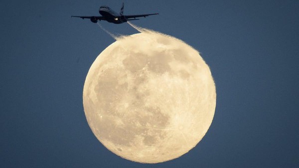 Sebuah pesawat terbang di langit diterangi cahaya bulan. Foto ini yang diambil di Richmond Park, London barat daya pada 8 Februari (Aaron Chown/PA/AP/CNN)