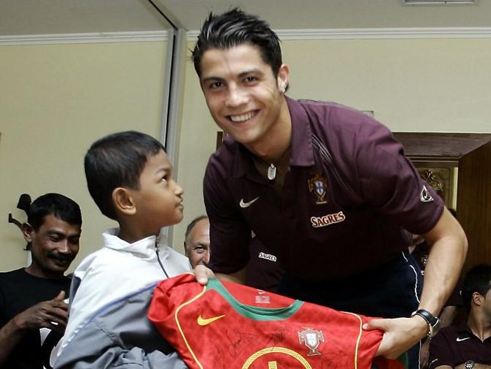 Portugal national soccer team and Manchester United striker Cristiano Ronaldo (R) poses with Martunis (L), a 7-year-old Indonesian tsunami survivor, in Lisbon 02 June 2005. Martunis, who was wearing a Portuguese soccer team jersey when he was rescued in the Indonesian province of Banda Aceh, following Decembers deadly tsunami, was invited to Portugal at the inspiration of player Luis Figo to attend the teams match on Saturday and to meet his idols. The boy was accompanied by his grandfather. (Photo by FRANCISCO PARAISO / AFP)