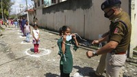 Seorang perwira polisi India membagikan masker kepada anak-anak dari pekerja upahan harian migran selama Lockdown di Jammu, India, Sabtu (28/3/2020). Perdana Menteri India Narendra Modi memutuskan Lockdown selama 21 hari. Kementerian keuangan India juga mengumumkan paket stimulus ekonomi 1,7 triliun ($ 22 miliar) yang akan mencakup pemberian jatah biji-bijian selama tiga bulan kepada 800 juta orang, sekitar 60% dari negara terpadat kedua di dunia. AP Photo/Channi Anand.