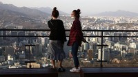 Warga mengenakan masker sambil menikmati matahari terbenam ketika orang Korea Selatan mengambil langkah untuk melindungi diri mereka sendiri dari penyebaran coronavirus (COVID-19) pada (27/3/2020) di Seoul, Korea Selatan. Pusat dan rumah sakit khusus Korea Selatan juga memusatkan peralatan dan personel khusus yang menjaga virus keluar dari rumah sakit. Sistem triase memastikan hanya mereka yang memiliki gejala parah yang dirawat di bangsal beroksigen rendah, diikuti karantina mandiri di rumah dengan akses ke konsultasi medis oleh semua orang.  Chung Sung-Jun/Getty Images.