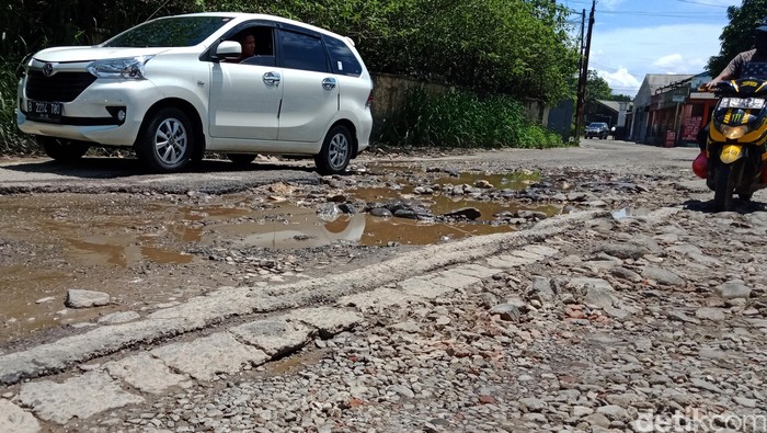 Jalan Raya Cibinong Tapos di perbatasan Cibinong-Depok tampak berlubang. Kendaraan pun terpaksa berjalan lambat saat melintasi jalan tersebut.