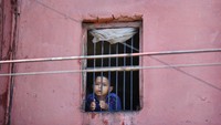 Seorang anak melihat keluar dari jendela rumahnya di kawasan kota tua Delhi setelah dikarantina di tengah pandemi Corona, di India, Jumat (27/3/2020). Beberapa legiun miskin India dan lainnya tiba-tiba dikeluarkan dari pekerjaan oleh seorang untuk tinggal di rumah secara nasional. AP Photo/Manish Swarup.