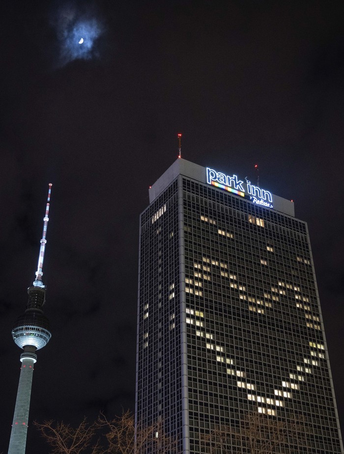 Park Inn Hotel di Berlin, Jerman, tidak lagi diizinkan menerima tamu seiring mewabahnya virus corona. Uniknya hotel ini memasang lampu berbentuk logo cinta di gedung mereka.