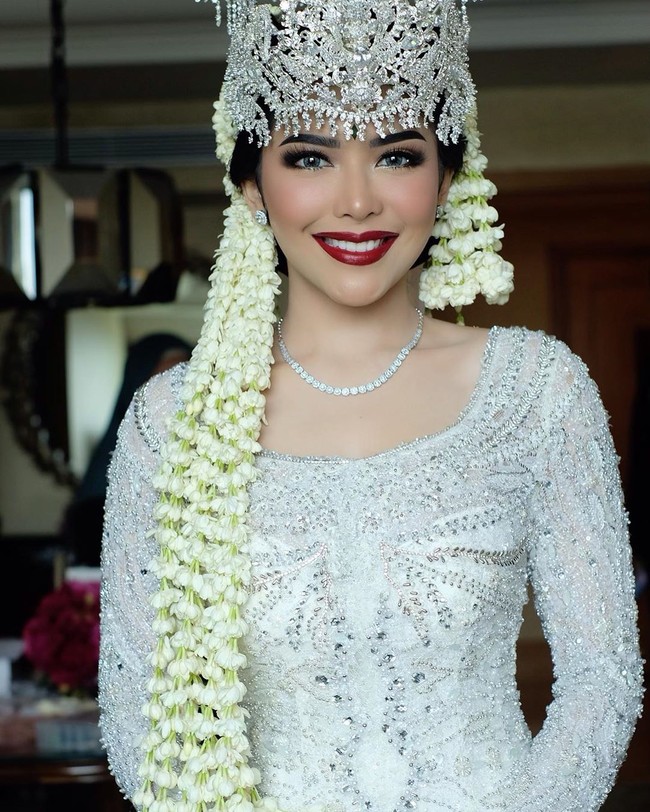 Saat akad nikah dengan Kompol Fahrul Sudiana, Rica Andriani tampil dengan gaya pengantin adat Sunda. Rica yang populer di Instagram dengan followers lebih dari 191 ribu itu terlihat mengenakan kebaya putih rancangan desianer Asky Febrianti dan siger karya Rinaldy A Yunardi. Foto: Instagram @bennusorumba