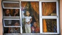 Warga melihat dari jendela apartemen mereka di Mannenburg, Cape Town, Afrika Selatan, Sabtu (28/3/2020). Afrika Selatan memutuskan lockdown total guna membatasi pergerakan publik selama 21 hari dalam upaya mengendalikan penyebaran COVID-19 Coronavirus. AP Photo.