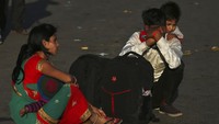 Seorang pekerja migran India membawa seorang anak di pundaknya ketika mereka menunggu transportasi ke desa mereka setelah di karantina di tengah kekhawatiran akan penyebaran virus Corona di New Delhi, India, Sabtu (28/3/2020). Pihak berwenang mengirim armada bus ke pinggiran kota. Ibukota India. Perdana Menteri Narendra Modi mengumumkan lockdown 21 hari dan membuat jutaan orang India yang hidup dari pendapatan harian tidak bekerja. AP Photo/Altaf Qadri.