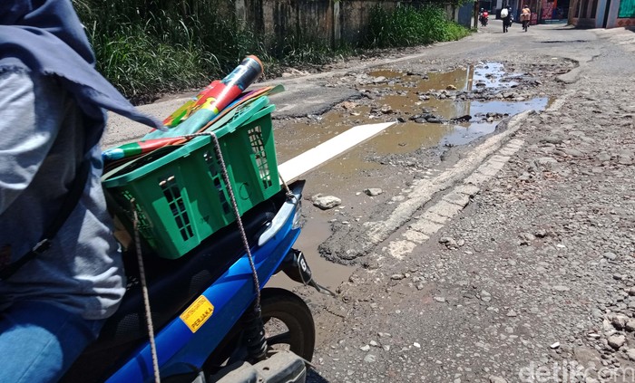 Jalan Raya Cibinong Tapos di perbatasan Cibinong-Depok tampak berlubang. Kendaraan pun terpaksa berjalan lambat saat melintasi jalan tersebut.